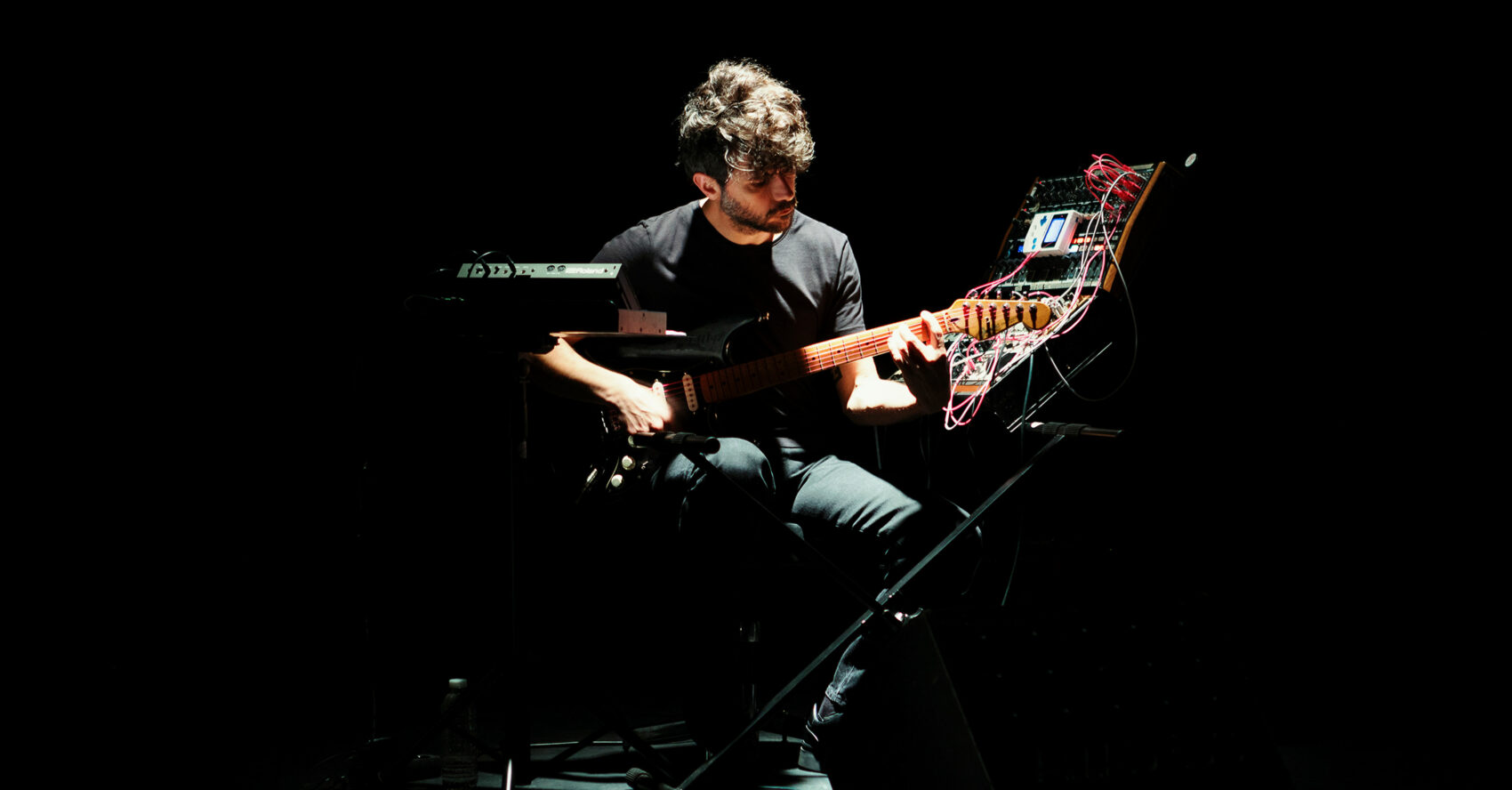 Photo sur scène du musicien avec des machines et une guitare électriques