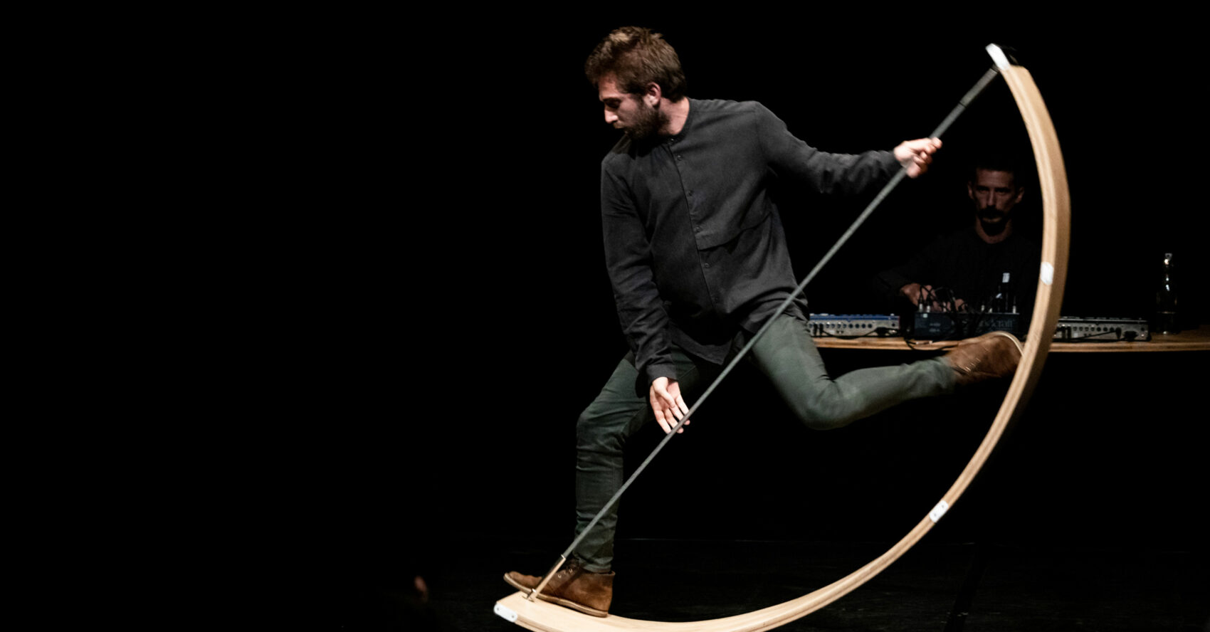 Un homme sur un arc en boit géant relié par un cable